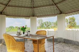 una mesa de comedor y sillas en una habitación con ventanas en StayVista's Gaudhuli Farmstay - Outdoor Pool & Terrace with View, 