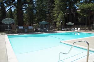 una gran piscina azul con sillas y sombrillas en #317 - Ski-In Ski-Out Pet-Friendly Condo with Spa, Sauna, Gym, Pool en Old Mammoth