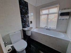 a bathroom with a tub and a toilet and a sink at 3 mins from the theme park! Charming Bedford Hideaway! in Kempston
