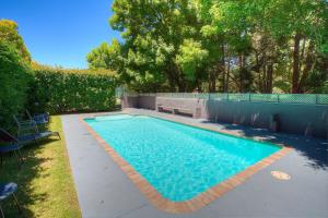 een zwembad met een bank in een tuin bij Grevillea Gardens Unit 4 in Bright