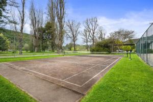 een tennisbaan met een net en gras bij Grevillea Gardens Unit 4 in Bright