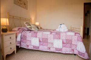een slaapkamer met een roze en witte quilt op een bed bij Locorotondo Home Holidays in Locorotondo