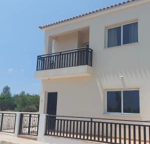 una casa blanca con un balcón con barandilla negra en The T Villa, en Protaras