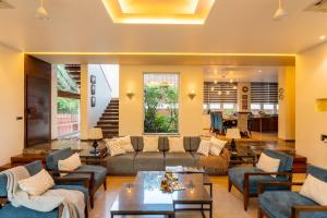 uma sala de estar com um sofá, cadeiras e uma mesa em Elivaas Dahlia Luxe 4BHK Villa with Pvt Pool near Baga em Arpora