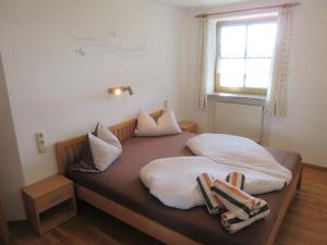 Schlafzimmer mit einem Bett mit weißer Bettwäsche und einem Fenster in der Unterkunft Geppingerhof in Waging am See