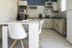 Castelsagrat的住宿－Ferme en pleine campagne，厨房配有白色的柜台和2把白色的椅子