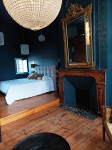 1 dormitorio con 1 cama con espejo y chimenea en LA MAISON DU SOLEIL, en LʼIsle-Jourdain