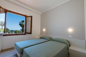 two beds in a room with a window at Residence Elle in San Benedetto del Tronto