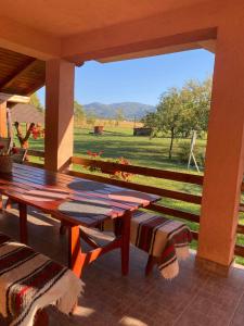 a wooden table and chairs on a porch with a view of a field at Pensiunea Martuca in Şurdeşti