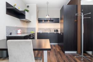 a kitchen with black cabinets and a wooden table at Apartamenty Platinum Inowroclawska Wrocław by Renters in Wrocław