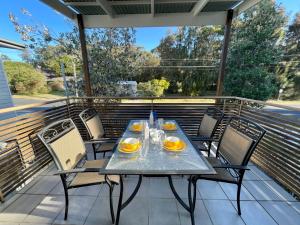 a table and chairs on a balcony with a table and chairs at Beach Retreat in Mollymook
