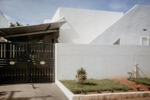 a white house with a black gate and a yard at RD VILLA in Perundurai