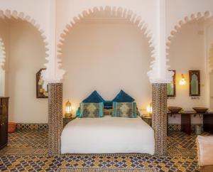 um quarto com uma cama branca e almofadas azuis em Hotel Blanco Riad em Tetouan