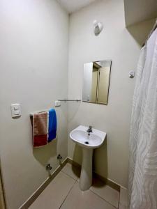 ein weißes Badezimmer mit einem Waschbecken und einem Spiegel in der Unterkunft Apartamento en Jesús María in Lima