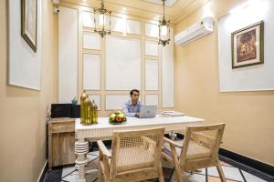 a man sitting at a table with a laptop at Dev Mahal - A Boutique Heritage Hotel in Jaipur