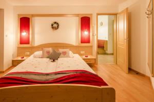 1 dormitorio grande con 1 cama grande con detalles en rojo en Voppichlhof App Alpenrose, en San Giacomo