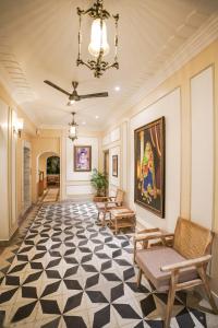 einen Flur mit einem großen Gemälde an der Wand und Stühlen in der Unterkunft Dev Mahal - A Boutique Heritage Hotel in Jaipur