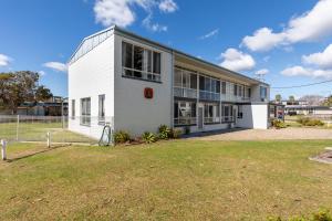a white building with a large yard in front of it at Fishpen Holiday Apartments in Merimbula