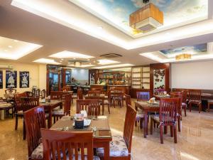 ホーチミン・シティにあるBon Ami Hotel - Thiên Xuân Hotelの天井のレストラン(木製のテーブルと椅子付)
