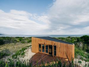 a small wooden house on a beach in a field at Studio Tasmania in Dolphin Sands