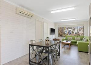 a dining room with a table and a green couch at Serene Nature Retreat in Rhyll