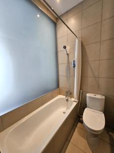 La salle de bains est pourvue d'une baignoire blanche et de toilettes. dans l'établissement Via Renata Panglima Polim, à Jakarta