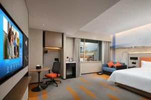 a hotel room with a bed and a flat screen tv at Hampton by Hilton Foshan Dali in Foshan