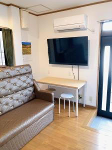 a living room with a couch and a desk with a tv at HOSTEL198 in Osaka