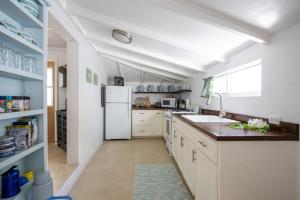 Lillian's Cottage cottage في جزيرة هاربور: مطبخ فيه دواليب بيضاء وثلاجة بيضاء