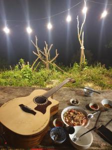 a guitar sitting on top of a table with food at Tuyên Chiến Home & Resort in Ấp An Kroët