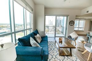 a living room with a blue couch and large windows at 2BR Uptown Furnished Apartment near Truist Fields apts in Charlotte