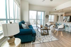 a living room with a blue couch and a kitchen at 2BR Uptown Furnished Apartment near Truist Fields apts in Charlotte