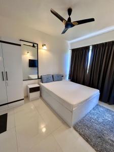 Good Stay 2 BHK Flat 301 في دابوليم: غرفة نوم بسرير ومروحة سقف