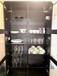 Good Stay 2 BHK Flat 301 في دابوليم: غرفة تخزين سوداء مع أطباق وأطباق على الأرفف
