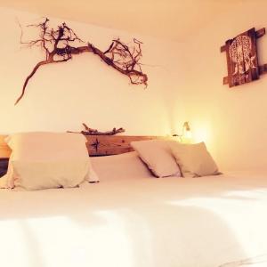 a bedroom with a bed with white sheets and a branch on the wall at Lodge bien être et nature in Soultzeren