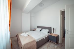 a white bedroom with a bed and a night stand at Palace of Culture Dream Apartments and Studios Iasi in Iaşi