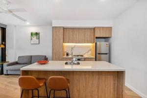 a kitchen with a kitchen island with two chairs at Above Broadbeach casino 1BRplus Study ocean-city views in Gold Coast