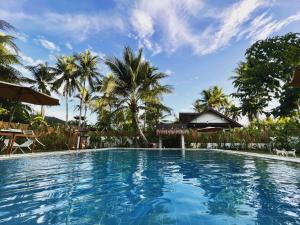 a large swimming pool with palm trees in the background at The Village Siargao in General Luna