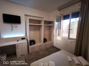 een kamer met een bed, een tv en een raam bij Residence IL CARRUBO in Gallipoli