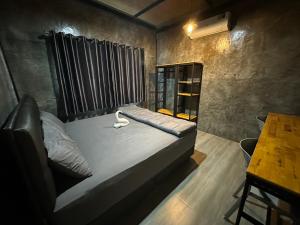 Cama pequeña en habitación con mesa en The Nack Resort & Pool Villa บางบัวทอง en Nonthaburi