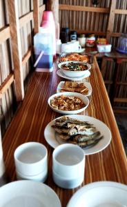 a long wooden table with plates of food on it at Aldejus Homestay in Yennanas Besir