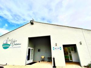 a white building with an open door with a patio at Hotel Aux Rochers de l'Ocean in Givrand