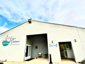 een wit gebouw met een open deur en een patio bij Hotel Aux Rochers de l'Ocean in Givrand