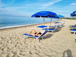a woman laying on a beach with chairs and umbrellas at Barko Apartments & Suites in Steccato