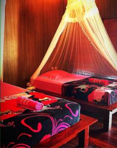 a bedroom with two beds with a canopy at Aldejus Homestay in Yennanas Besir