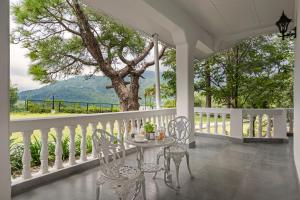 stół i krzesła na ganku z drzewem w obiekcie Brij Anayra Dharamshala - A Himalayan Luxury Retreat w mieście Dharamsala