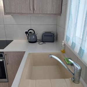 a kitchen counter with a sink and a tea kettle at ALEX FRUIT TREE HOME in Voroklini