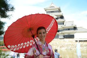 une femme en kimono portant un parapluie rouge dans l'établissement Hotel Montagne Matsumoto, à Matsumoto