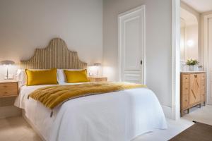 1 dormitorio blanco con 1 cama grande con almohadas amarillas en Magno Apartments Casa Pilatos, en Sevilla