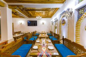 a restaurant with blue tables and chairs and a flat screen tv at AL-HAYAT in Bukhara